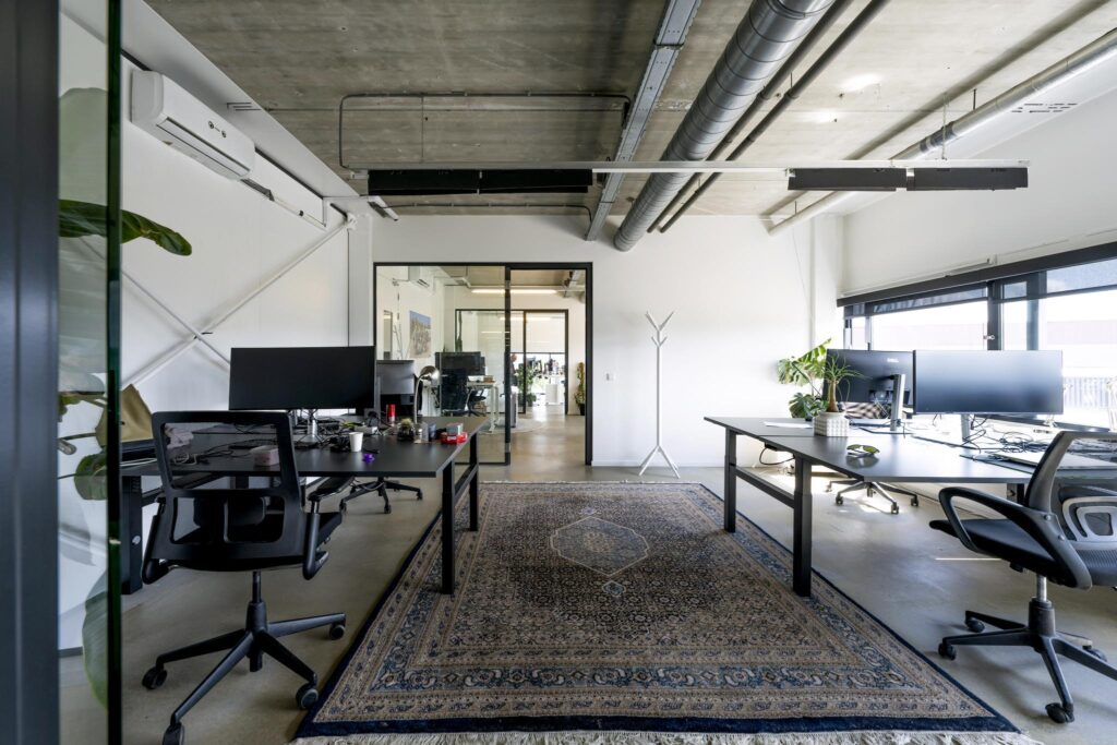 Modern open office space on Johan van Hasseltweg with desks, computers, and industrial-style ceiling.